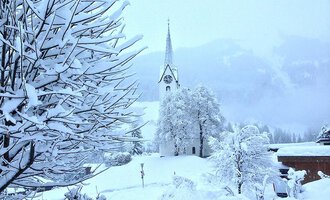 © Jockl Metzger A snowy landscape with a church in the background. Trees and bushes are completely covered in snow. | © Jockl Metzger