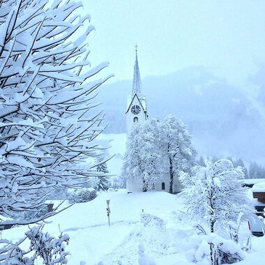 © Jockl Metzger A snowy landscape with a church in the background. Trees and bushes are completely covered in snow. | © Jockl Metzger