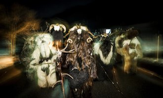 © Kleinwalsertal Tourismus | Dominik Berchtold A group of people in animal-like costumes is walking at night. The costumed figures have horns and are part of a festive parade. | © Kleinwalsertal Tourismus | Dominik Berchtold