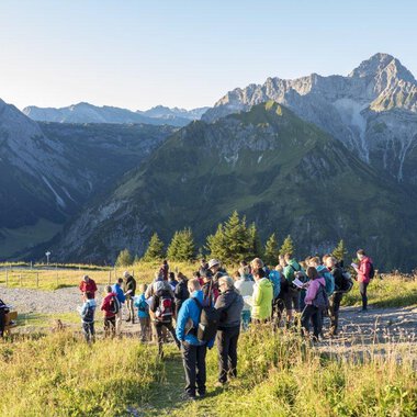 Eine Gruppe von Wanderern genießt die Aussicht auf die Berge. Der Himmel ist klar und die Natur bietet eine beeindruckende Kulisse. | © OK-Bergbahnen