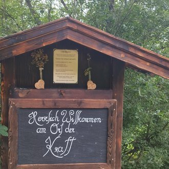 © Nicole Lughammer Ein traditionelles Holzschild mit der Aufschrift "Herzlich Willkommen an den Ötztal". Umgeben von grünen Bäumen und einer ländlichen Umgebung. | © Nicole Lughammer
