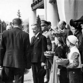 © Kleinwalsertal Tourismus | Karl Max Kessler Archiv Ein historisches Gebäude mit einem Charakteristikum von schneebedeckten Straßen und einem Kirchturm im Hintergrund. Menschen sind in der Szene unterwegs. | © Kleinwalsertal Tourismus | Karl Max Kessler Archiv