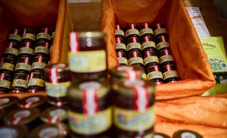 © Kleinwalsertal Tourismus | Oliver Farys A variety of small jars of jam are placed in orange baskets. The jars are arranged in rows and have colored labels. | © Kleinwalsertal Tourismus | Oliver Farys