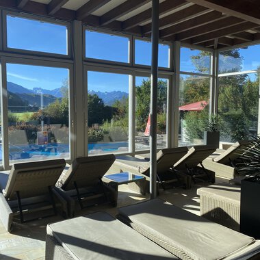 Ein heller Ruhebereich mit Liegen und großen Fenstern. Im Hintergrund sind Berge und ein Pool zu sehen. | © Wonnemar Sonthofen | interSPA Gruppe