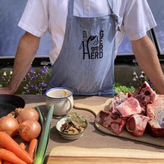 © Gerd am Herd | Gerd Hammerer Ein Koch steht an einem Tisch mit frischen Zutaten, darunter Gemüse und Fleisch. Im Hintergrund sind Blumen und eine helle Umgebung sichtbar. | © Gerd am Herd | Gerd Hammerer