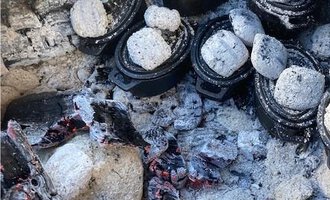 Mehrere kleine Töpfe liegen in einer Asche- und Kohlenglut. Die Szene vermittelt einen Eindruck vom Kochen über dem offenen Feuer. | © Gerd am Herd | Gerd Hammerer