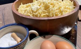 Eine Holzschüssel mit frisch geriebenem Käse steht auf einem Tisch. Daneben liegen eine Schüssel mit Eiern und ein Behälter mit Salz. | © Gerd am Herd | Gerd Hammerer