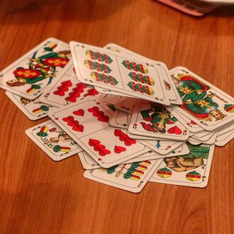 © Chesa Valisa A stack of cards lies on a wooden table. A hand is visible, encircling the cards. | © Chesa Valisa