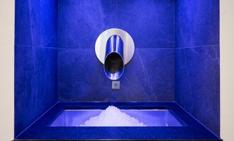 Ein moderner Eiswürfelspender mit einer silbernen Öffnung. Die Umgebung ist in blauem Licht beleuchtet und hat eine elegante Steinoberfläche. | © Hotel Erlebach GmbH