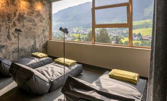 Ein gemütlicher Raum mit entspannenden Liegen und Blick auf die Berge. Große Fenster lassen viel Tageslicht herein. | © Hotel Erlebach GmbH