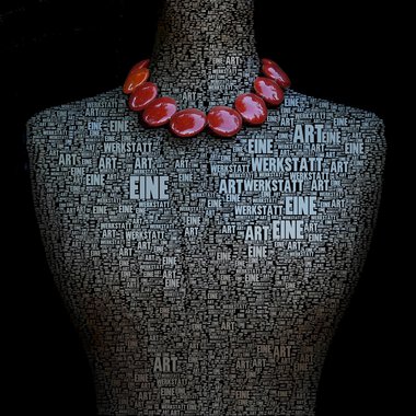 Eine kunstvolle Darstellung eines Mannequins, das mit Worten über Kunst bedeckt ist. Es trägt eine auffällige Kette aus roten Perlen. | © Gerti Maitz