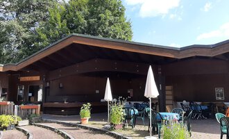 Ein gemütliches Café mit einer Holzfassade und Terrassenmöbeln. Umgeben von Pflanzen und Bäumen, lädt es zum Entspannen ein. | © Kulturcafe Kleinwalsertal | Veronika Senn