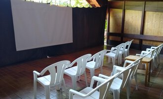 Ein Raum mit weißen Kunststoffstühlen und einer Leinwand. Die Umgebung ist ruhig und eignet sich gut für Präsentationen oder Filme. | © Kulturcafe Kleinwalsertal | Gerhard Bauer