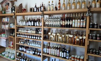A shelf with different types of bottles containing liqueurs and spirits. Next to the bottles, there are also jams and other products. | © Abler Mitbringsel Riezlern | Veronika Senn