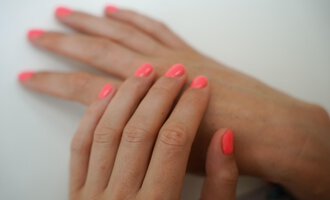 Two hands with bright neon pink nail polish are placed on top of each other. The background is bright and neutral. | © Annett Schwärzler Nails & Spa | Stefanie Haid