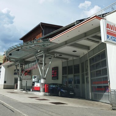 Eine moderne Tankstelle mit einer großen Überdachung steht an einer ruhigen Straße. Im Hintergrund sind Wohngebäude und ein bewölkter Himmel zu sehen. | © Kleinwalsertal Tourismus | N. Lughammer