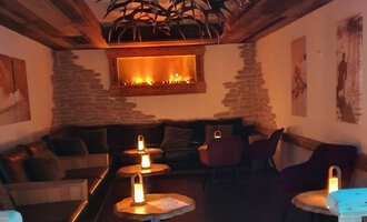 A cozy room with a warm atmosphere. There are comfortable seats and soft light from candles. | © Hotel Steinbock