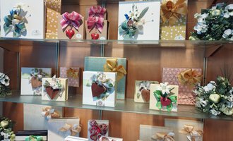 A display case with beautifully wrapped gifts in various colors and adorned with artistic bows. The gifts come in different sizes, and some have heart or floral motifs. | © Kleinwalsertal Tourismus | N. Lughammer