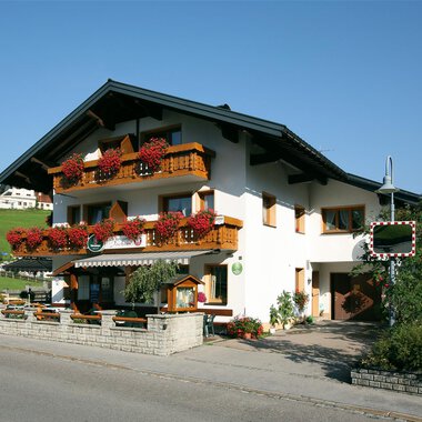 A picturesque building in alpine style with blooming balconies. It is situated in a quiet, green surrounding. | © Cafe Jochum | Bernadette Reinmuth