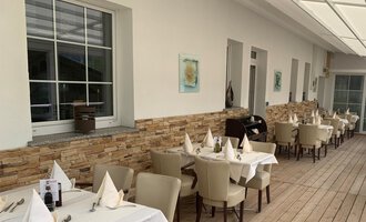 Ein elegantes Restaurant mit Holzboden und hellen Tischen. Die Wände sind mit sanften Farbtönen dekoriert und es gibt große Fenster für viel Tageslicht. | © Ristorante Trentino | Dietmar Jochum