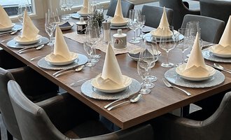 Ein elegant gedeckter Tisch mit Faltservietten und Gläsern. Der Tisch ist für eine festliche Veranstaltung vorbereitet.