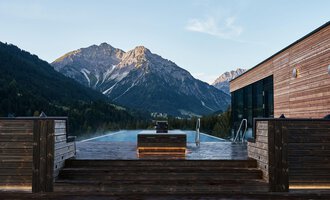 An infinity pool with a view of majestic mountains. The wooden veranda creates a cozy atmosphere in nature. | © Travel Charme Ifen Hotel