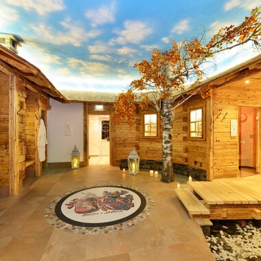 A cozy wellness area with wooden paneling and beautiful tree decorations. The ceiling features a clear sky, creating a relaxing atmosphere. | © Hotel Alpenstüble Appartements | Manuel Riezler