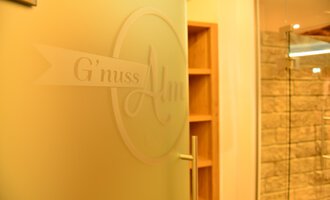 A door with the inscription "G'nuss Alm" is visible in the image. The area seems to be inviting and modernly designed. | © Hotel Alpenstüble Appartements | Manuel Riezler