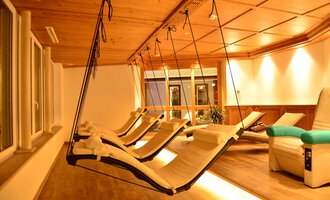 A cozy relaxation room with hanging loungers and warm light. The wooden ceiling creates a relaxing atmosphere. | © Hotel Alpenstüble Appartements | Manuel Riezler