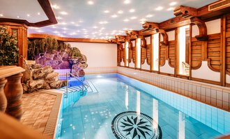 A beautiful indoor pool with clear, blue water and decorative wooden elements. The atmosphere is calm and inviting, perfect for relaxing.