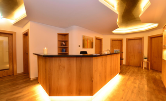 A modern reception area with a wooden counter and soft lighting. The walls are kept neutral, creating an inviting atmosphere.