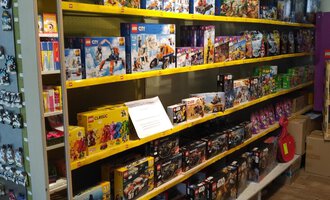 A shelf with various LEGO sets in a store. There is a variety of themes and colors. | © Der Bunte Laden | Romana Volderauer
