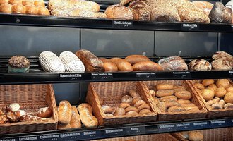 A selection of different types of bread in a bakery. The shelves are full of fresh rolls and loaves. | © Ehrat´s Backmanufaktur | Veronika Senn