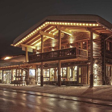 A charming wooden building with warm light at night. The facade is cozy and inviting. | © Fun-Alp