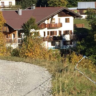 An idyllic house amidst colorful autumn leaves. The garden is well-maintained and the building has a traditional Alpine style. | © Gasthof Café Alpenwald | Thorsten Alpenwald