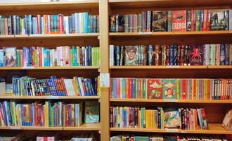 A bookshelf with many colorful books. The books are neatly arranged in several rows. | © Kleinwalsertal Tourismus | N. Lughammer