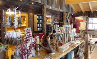 A cozy shop with rustic wooden furniture and decorative items.  
There is a variety of Christmas and home accessories on the shelves.