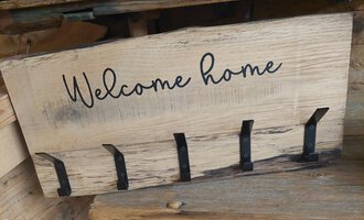 A wooden sign with the inscription "Welcome home" and five hooks underneath. It conveys an inviting feeling for the entrance area.