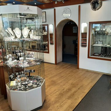 A jewelry store with a jewelry display in the center. Additional pieces of jewelry are displayed in showcases on the walls. | © Juwelier Demsky Walser Goldschmiede| Veronika Senn