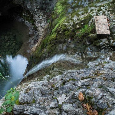 A rocky cliff with flowing water that leads into a deep, dark pool. Green moss and plants grow between the stones. | © Kleinwalsertal Tourismus | Andre Tappe