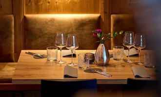 A beautifully set table in a cozy restaurant. It is decorated with glasses, cutlery, and a vase of flowers. | © La Vallée | Annette Sandner