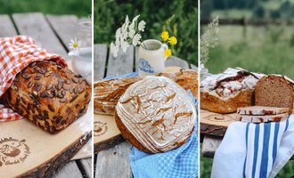 Three different breads are arranged on a wooden table. In the background, green meadows and wildflowers can be seen. | © Mahdtalhaus | Thomas Dielmann