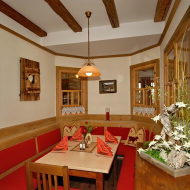 A cozy restaurant area with red upholstery and a wooden parlor design. The warm lights and the decor create an inviting atmosphere. | © Michl das Steakhaus | Johannes Littich