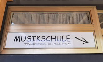 A sign with the inscription "MUSIC SCHOOL" points to a music school. The address is also provided. | © Kleinwalsertal Tourismus | Veronika Senn