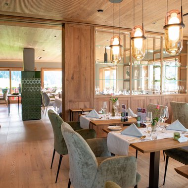 A modern restaurant with elegant wooden furnishings. The tables are lovingly set, and the lighting is warm and inviting. | © Almhof Rupp | Lukas Kind