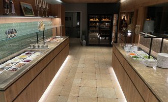 A modern designed buffet area with wooden shelves and a beautiful glass front. Various dishes and fresh ingredients are arranged on the tables. | © Almhof Rupp | Lukas Kind
