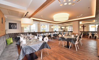 An elegant restaurant with wooden floors and modern tables. The tables are beautifully set and the lighting is soft. | © Hotel Neue Krone GmbH | Werbewind GmbH
