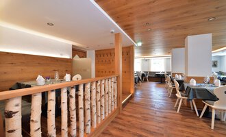 A modern designed restaurant with wooden walls and an inviting atmosphere.  
Tables are set with covered plates, and the floor is made of wood. | © Hotel Neue Krone GmbH | Werbewind GmbH