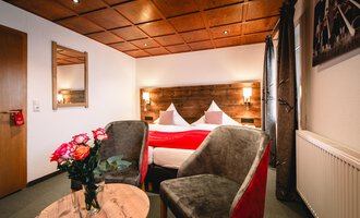 A cozy bedroom with a double bed and modern furniture. Two armchairs and a table complement the warm atmosphere.