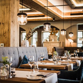 A stylish restaurant with elegant tables and comfortable seating. The cozy atmosphere is enhanced by soft lighting and natural materials. | © Verwöhn- & Wellnesshotel Walserhof| Aileen Melucci